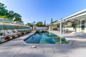 Ein Swimmingpool mit Sonnenschirm, Liegestühlen und einer überdachten Terrasse.