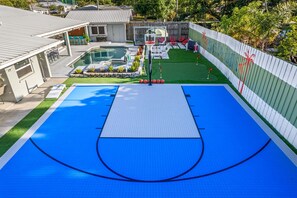 Ein Basketballfeld mit Pool, Sitzgelegenheiten im Freien und einem eingezäunten Bereich mit Wandmalerei.