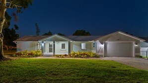 A two-story house with a garage, a well-maintained lawn, and a clear night sky. - Sleeps 20 Basketball Court Pool Movie Room (Bradenton)