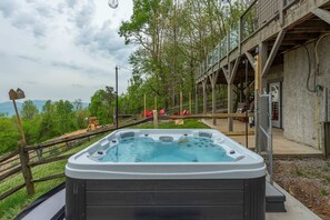 A hot tub with a wooden deck and a view of a forested area. - Sleeps 20 Hot Tub Outdoor Theater Fire Pit Games (Fairview)