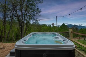 Ein Whirlpool mit Blick auf einen Wald und Berge im Hintergrund.