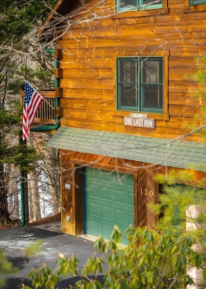 A wooden cabin with a green door, a sign reading 'ONE LAST RUN', and an American flag. - Mtn Retreat Movie Theater Arcade Hot Tub Slps 10 (McGaheysville)