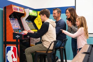 Una familia jugando a una máquina recreativa de NBA JAM.