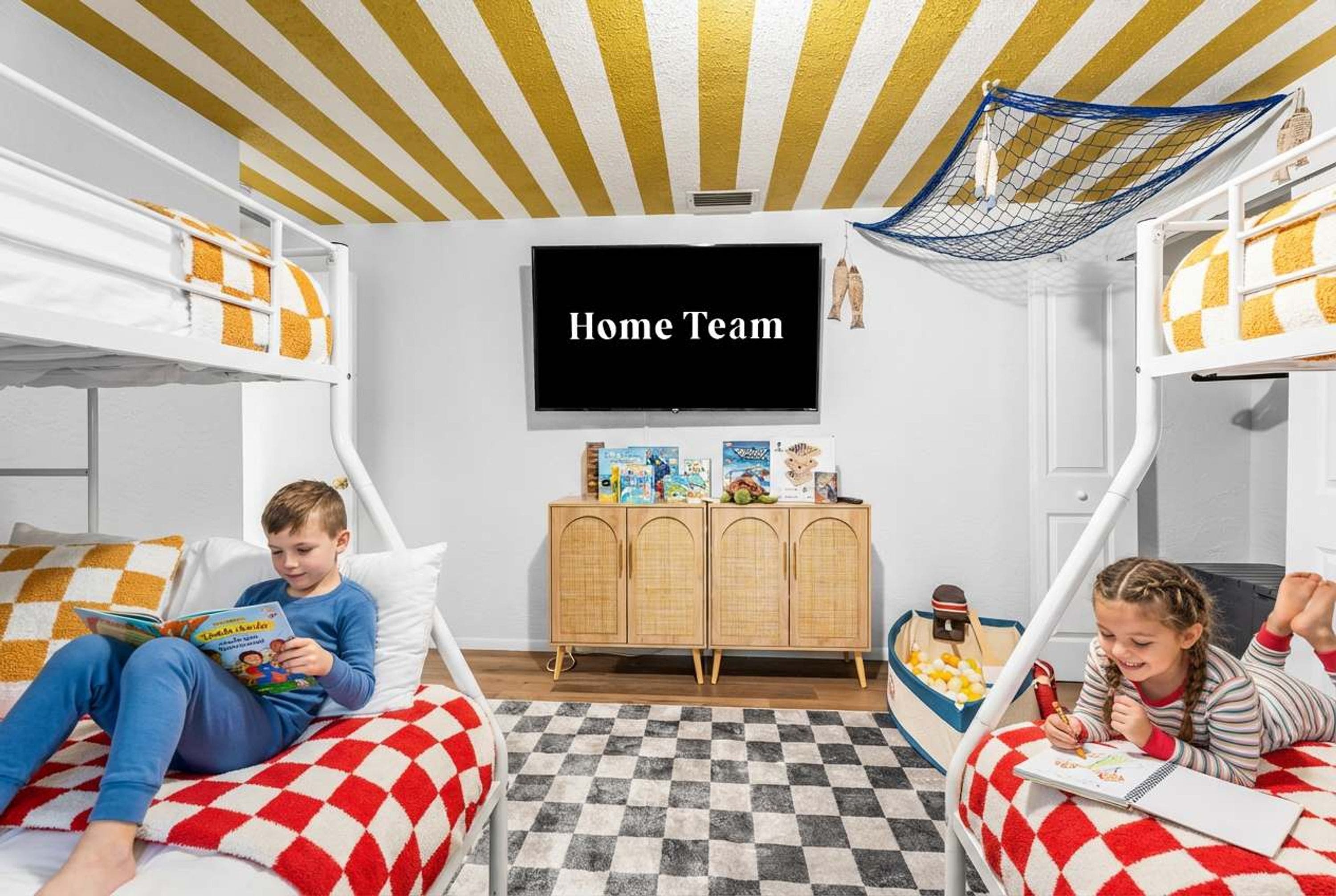 A room with bunk beds, a television, a cabinet with children's toys, and a checkered rug.