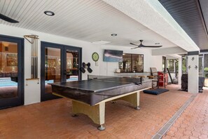 A billiards table in a room with a pool table, a dartboard, and a ceiling fan. - Tampa Oasis Private Pool Sauna Sleeps 14 (Tampa)