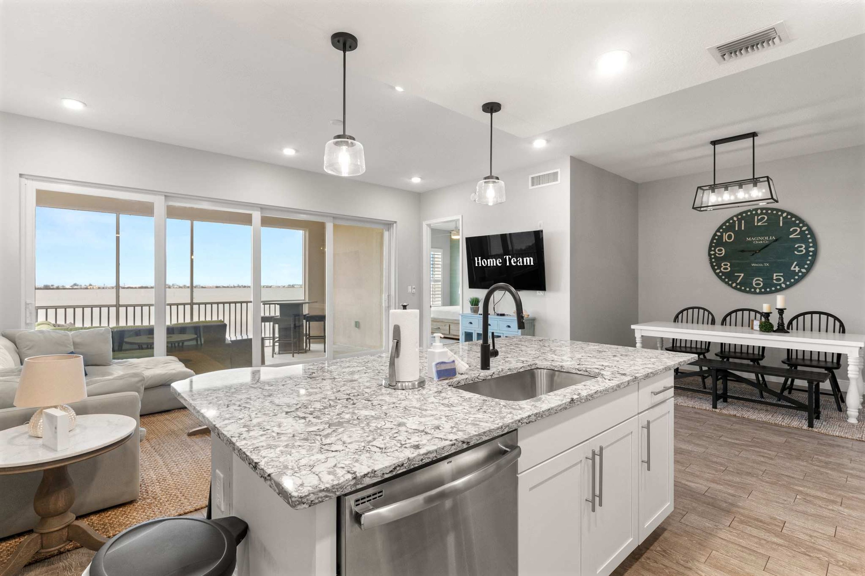 A modern kitchen with a large island, stainless steel appliances, and pendant lighting.
