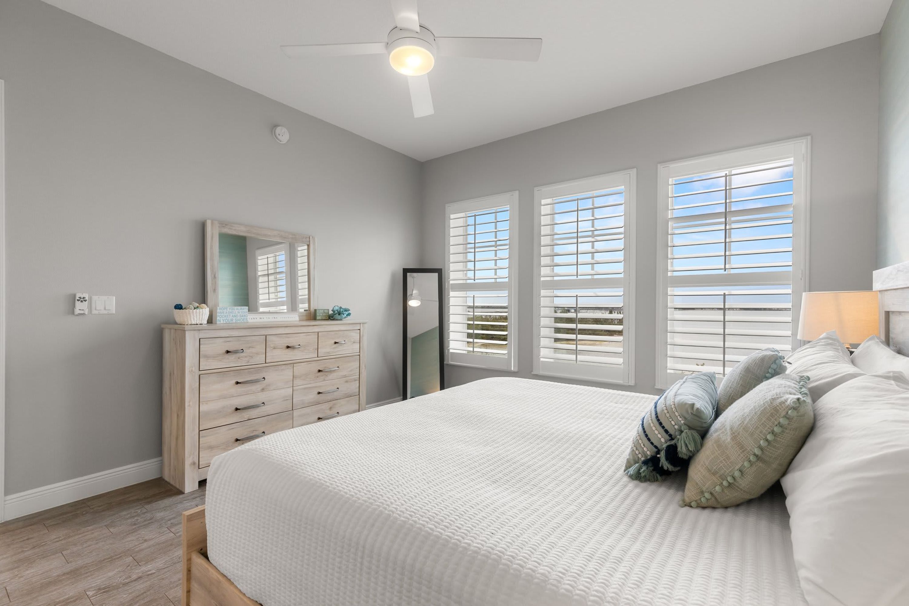A bedroom with a bed, dresser, and a ceiling fan.