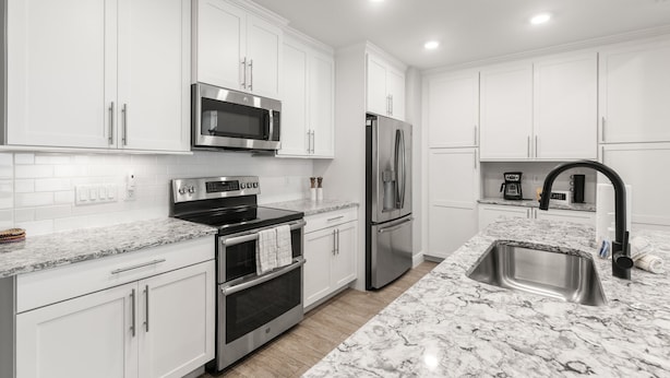 A modern kitchen with white cabinetry, stainless steel appliances, and a marble countertop. - Bradenton Retreat-pool Stunning Views More (Bradenton)