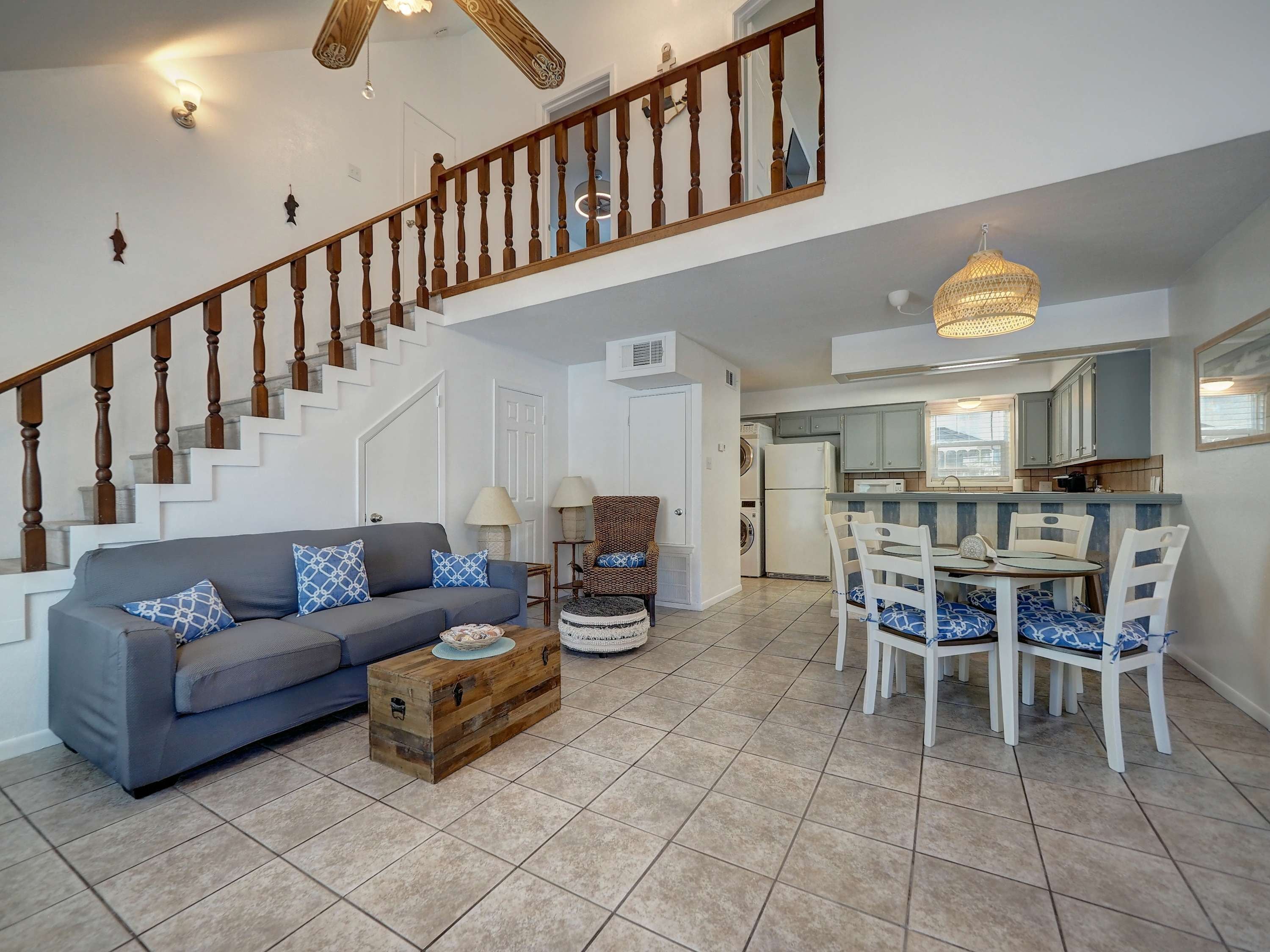 A spacious living area with a staircase, a dining table with chairs, and a kitchen area.
