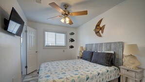 A bedroom with a bed, a ceiling fan, a window, wall art, a nightstand, and a lamp. - Canal Views Pool 2 Min to Beach Fishing Pier (Corpus Christi)