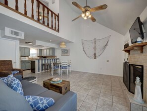 A spacious living area with a sofa, dining table, kitchen in the background, and a ceiling fan.