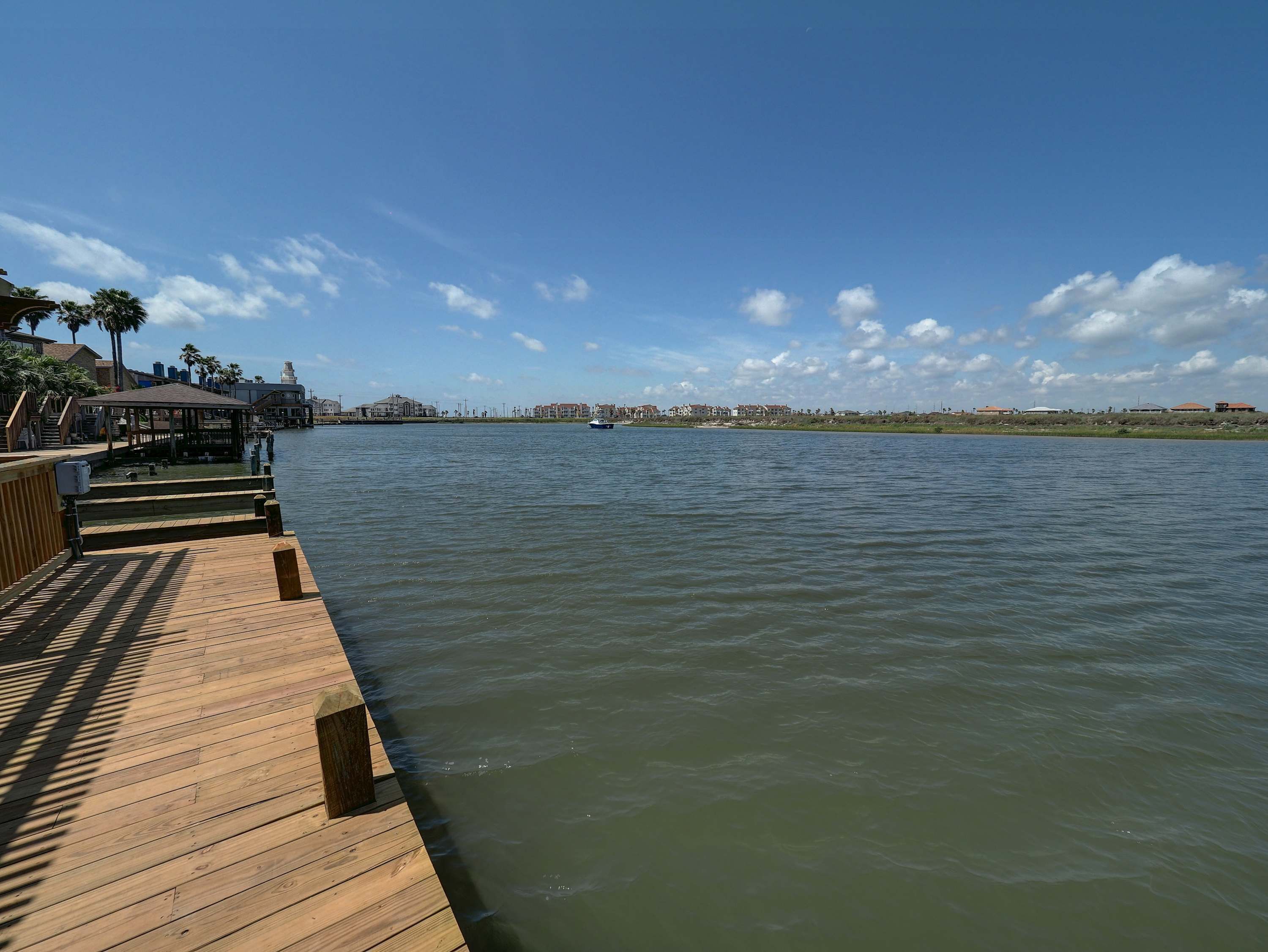 Een houten steiger die zich uitstrekt over rustig water, met een stadsgezicht op de achtergrond.