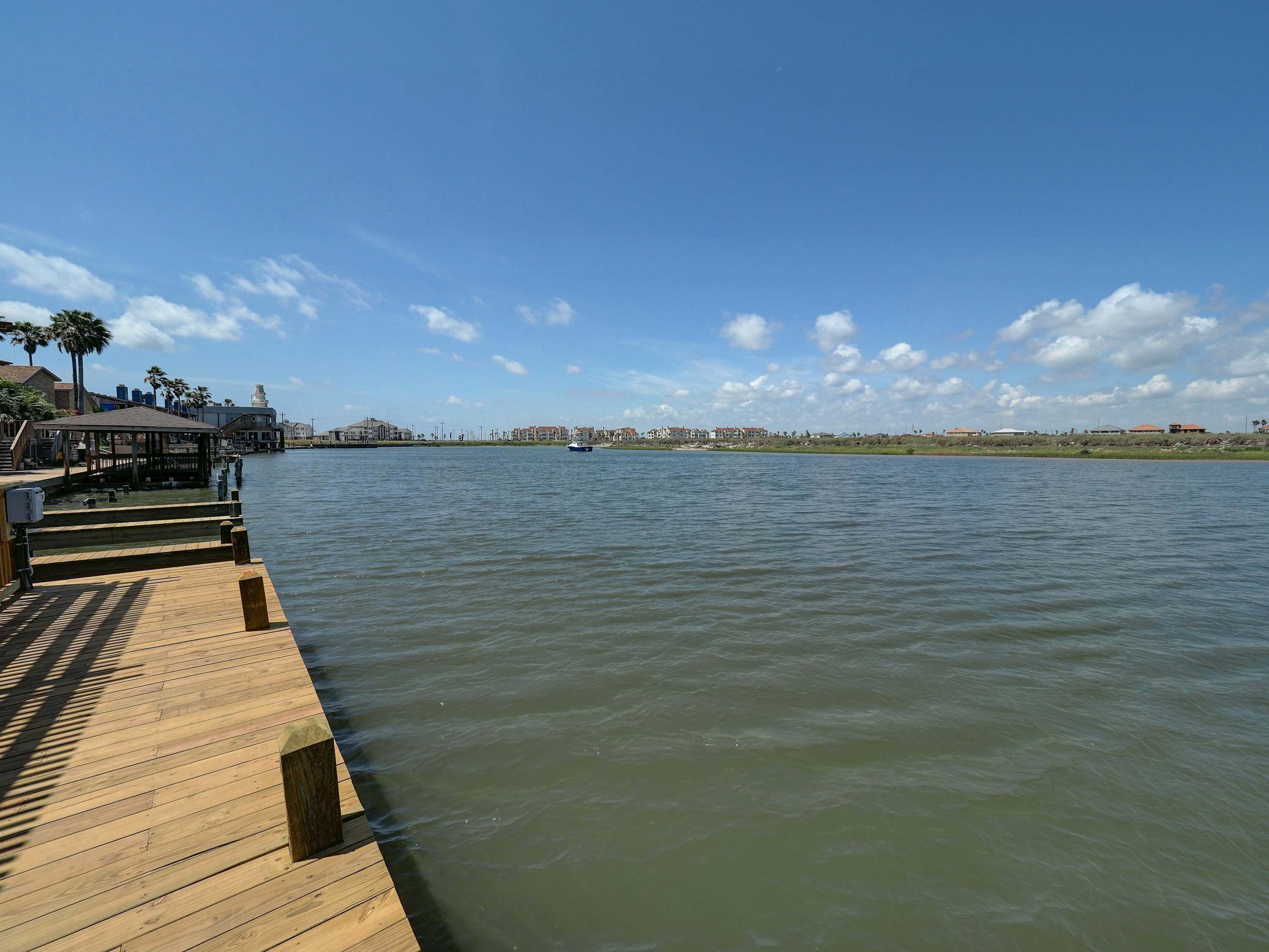 Een houten steiger die zich uitstrekt in kalm water onder een heldere lucht.