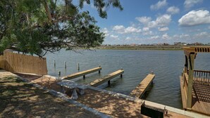 A waterfront park with wooden benches, a grill, and a wooden fence. - Canal Views Pool 2 Min to Beach Fishing Pier (Corpus Christi)