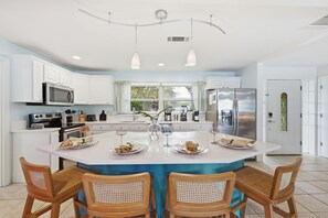 A modern kitchen with white cabinetry, a central island with chairs, and a large refrigerator. - Basketball Court Game Room Pool Hot Tub (Largo)