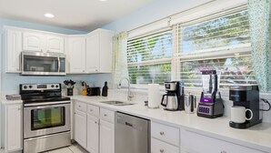A modern kitchen with white cabinets, a microwave, a stove, a dishwasher, and a coffee maker. - Basketball Court Game Room Pool Hot Tub (Largo)