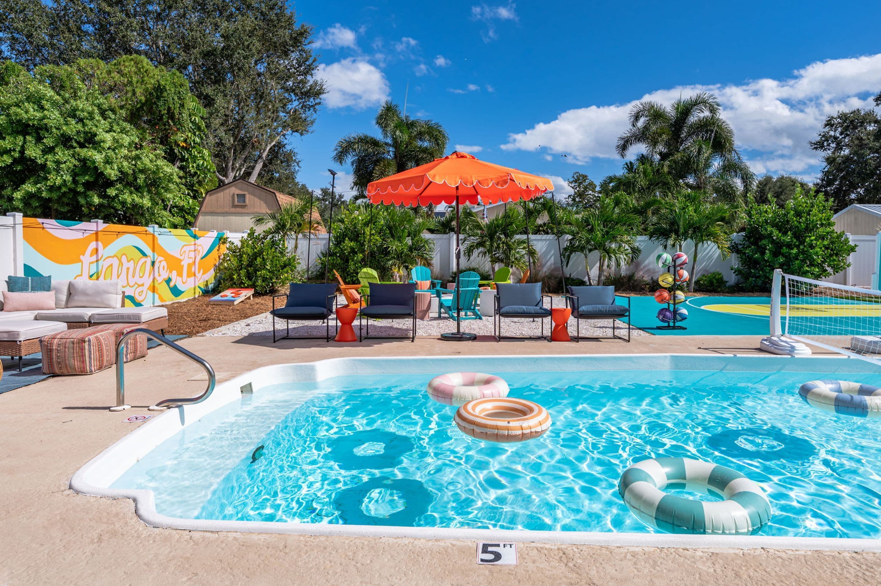 Une piscine avec des chaises longues et une fresque colorée en arrière-plan.