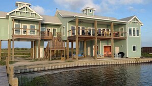 A waterfront property with multiple levels, outdoor seating, and a dock. - Waterfront Getaway With Pier Access (Aransas Pass)