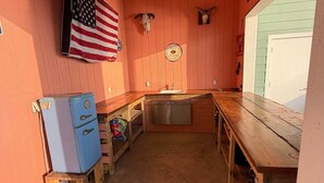 A compact kitchen with wooden walls, a sink, a refrigerator, and a window. - Waterfront Getaway With Pier Access (Aransas Pass)
