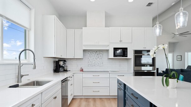 A modern kitchen with white cabinetry, a built-in microwave, and a coffee maker. - Waterfront Getaway With Pier Access (Aransas Pass)