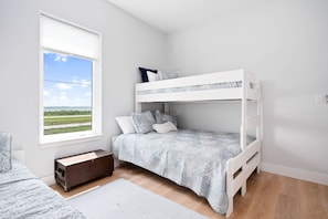 Een stapelbed in een kamer met uitzicht op een landschap door een raam.