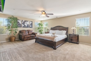 A bedroom with a large bed, a leather sofa, two potted plants, and a ceiling fan. - Minutes to Wineries Outdoor Oasis Pool Table (Murrieta)