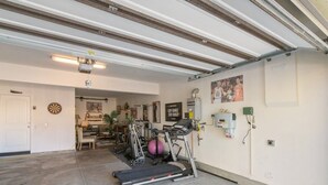 Eine Garage mit Laufband, Ergometer und Basketballkorb.