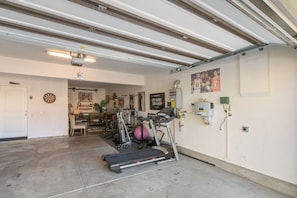 A garage with a treadmill, exercise bike, and a basketball hoop. - Minutes to Wineries Outdoor Oasis Pool Table (Murrieta)