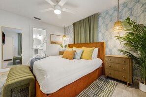 Ein modernes Schlafzimmer mit einem großen Bett, Nachttischen, einem Spiegel und einem Deckenventilator.