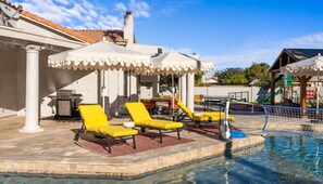 Zona de piscina amb gandules, una barbacoa i una zona de jocs per a nens.