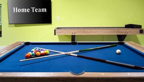 A pool table with balls and cues, a 'Home Team' sign, and a wooden table against a green wall. - Sleeps 19 Pool Sport Court Putt Putt Gym (Mesa)