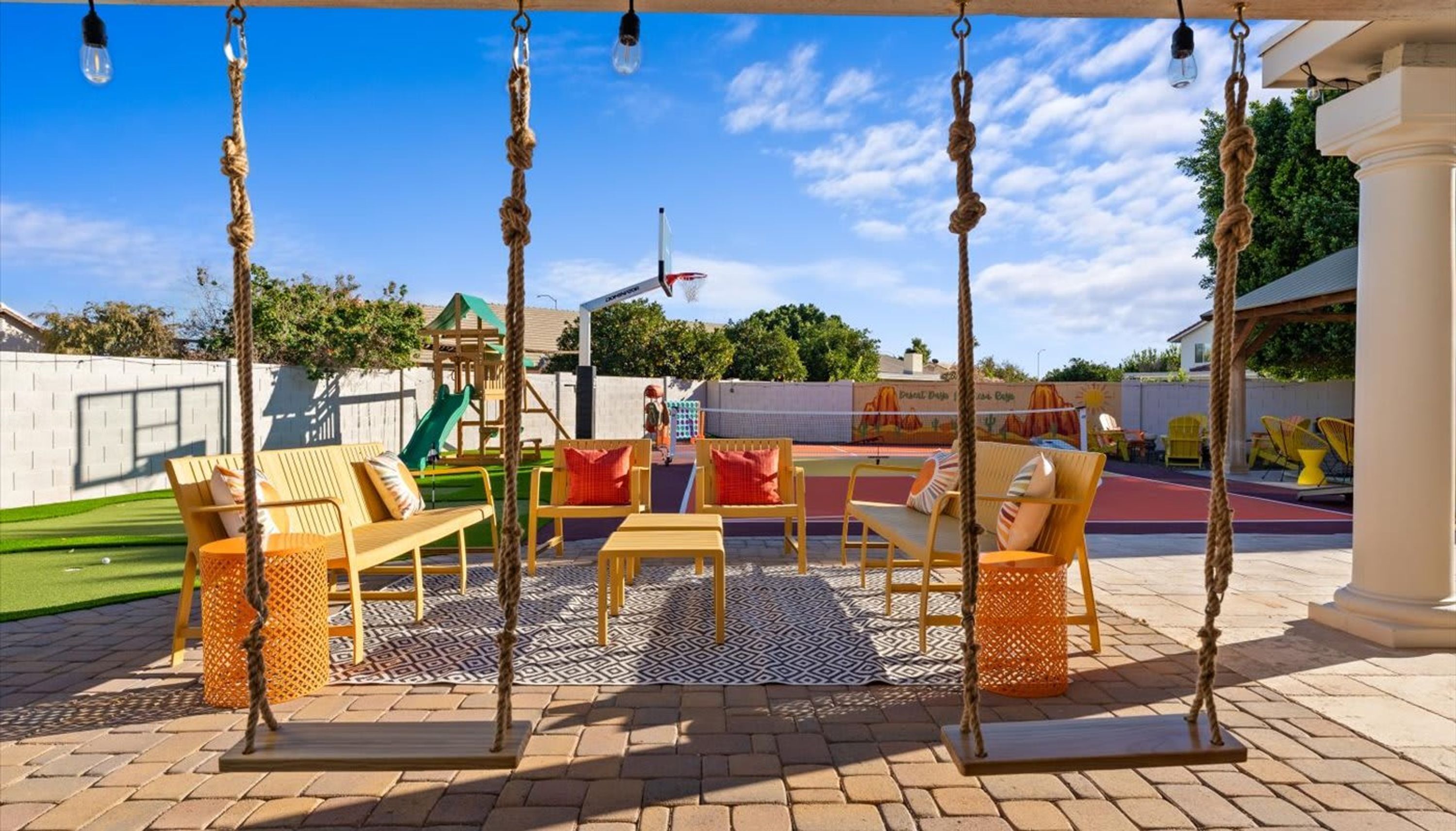 Eine Terrasse mit Schaukeln, einem Spielbereich und Sitzgelegenheiten im Freien.