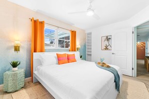 A bedroom with a bed, a ceiling fan, a window with curtains, a bedside lamp, and a wall-mounted shelf. - Playcation Putt Putt Pool Tiki Bar Game Room (Largo)