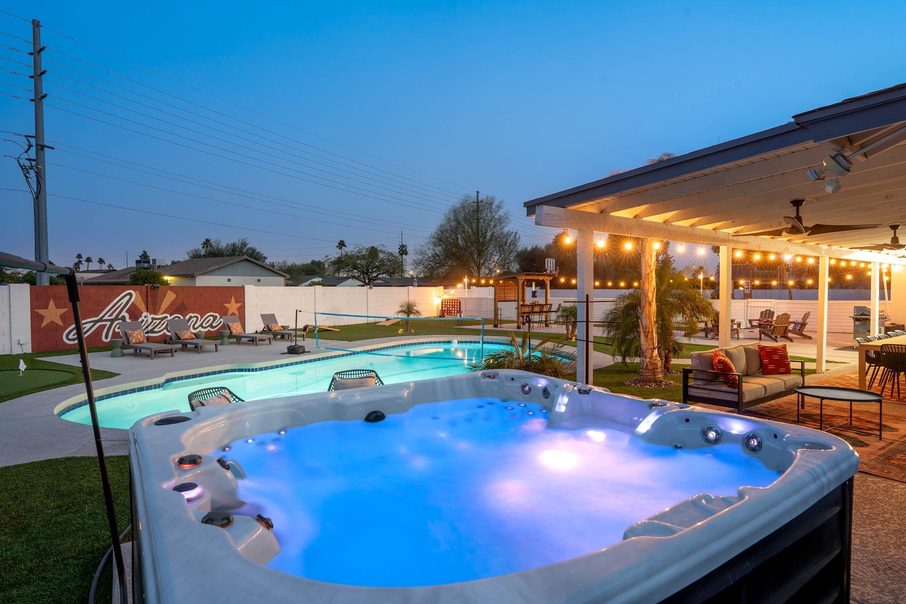 Ein Garten mit Schwimmbad, Whirlpool, Sitzgelegenheiten im Freien und einer überdachten Terrasse.
