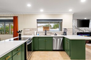 A modern kitchen with green cabinets, a stainless steel dishwasher, and a built-in oven. - The Ridge Family Pickleball Pool Hot Tub (Phoenix)
