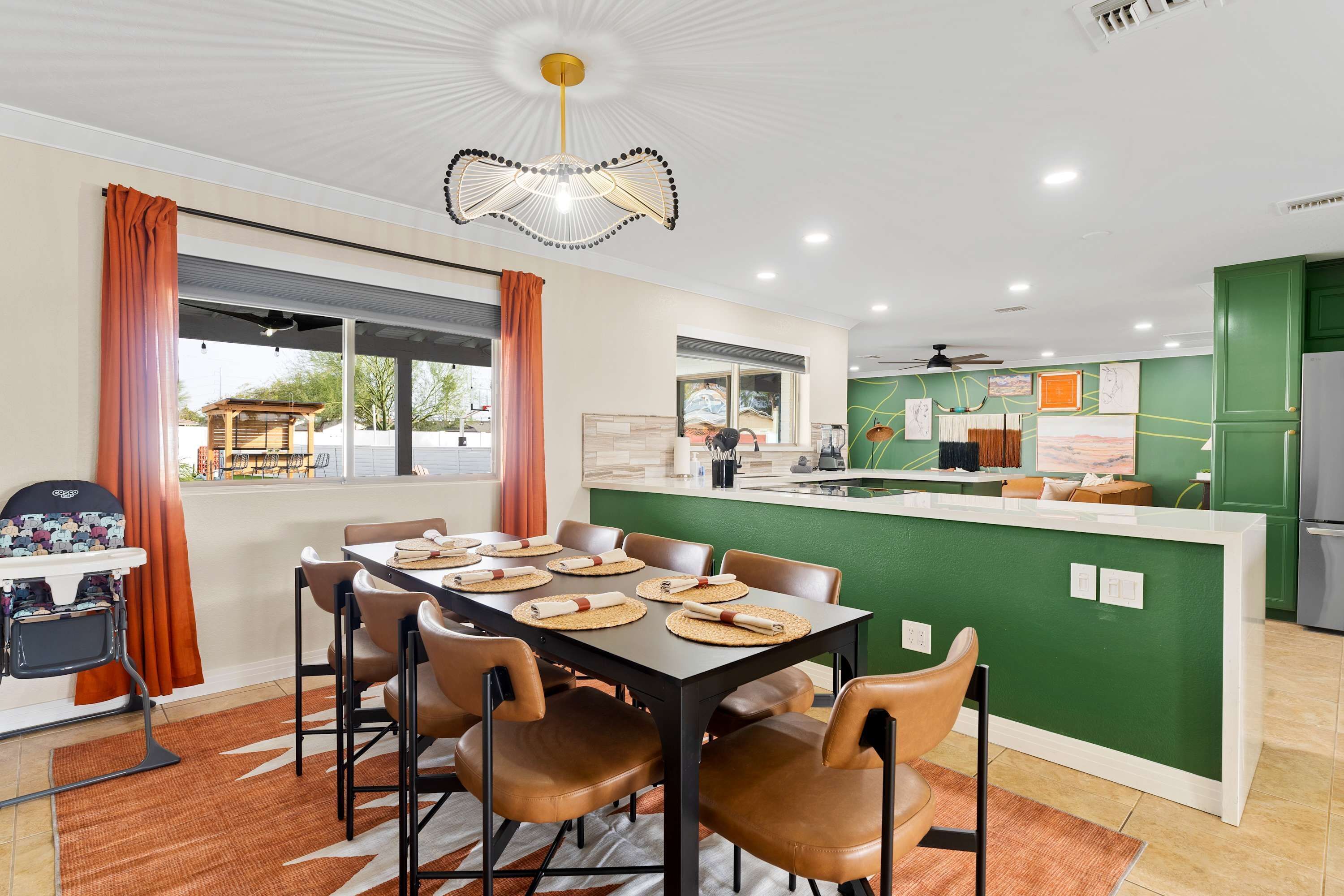 Uma cozinha moderna com uma ilha central, uma área de refeições com mesa posta para seis pessoas e vista para o exterior.