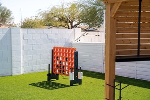 Ein eingezäunter Garten mit Kunstgrasanlage, einer Holz-Pergola und einer Kletterkonstruktion.