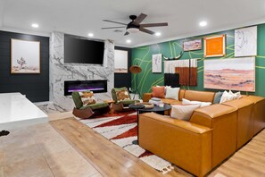 A modern living room with a fireplace, a sofa set, and artwork on the walls. - The Ridge Family Pickleball Pool Hot Tub (Phoenix)