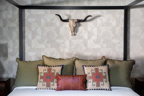 Ein Bett mit Kopfteil, zwei Zierkissen und eine Wand mit geometrischem Muster.