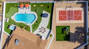 Luftaufnahme eines Anwesens mit Schwimmbad, Tennisplatz und Sitzbereich im Freien.
