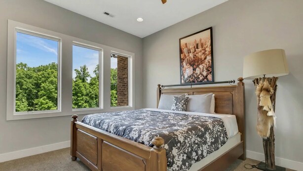 Quarto com uma janela grande, uma cama, cabeceira, um quadro e um abajur.