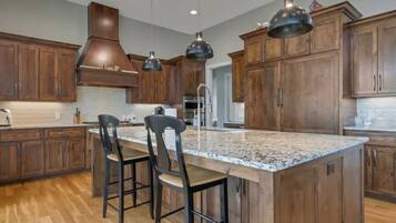A modern kitchen with wooden cabinets, a large island with bar stools, and pendant lighting.