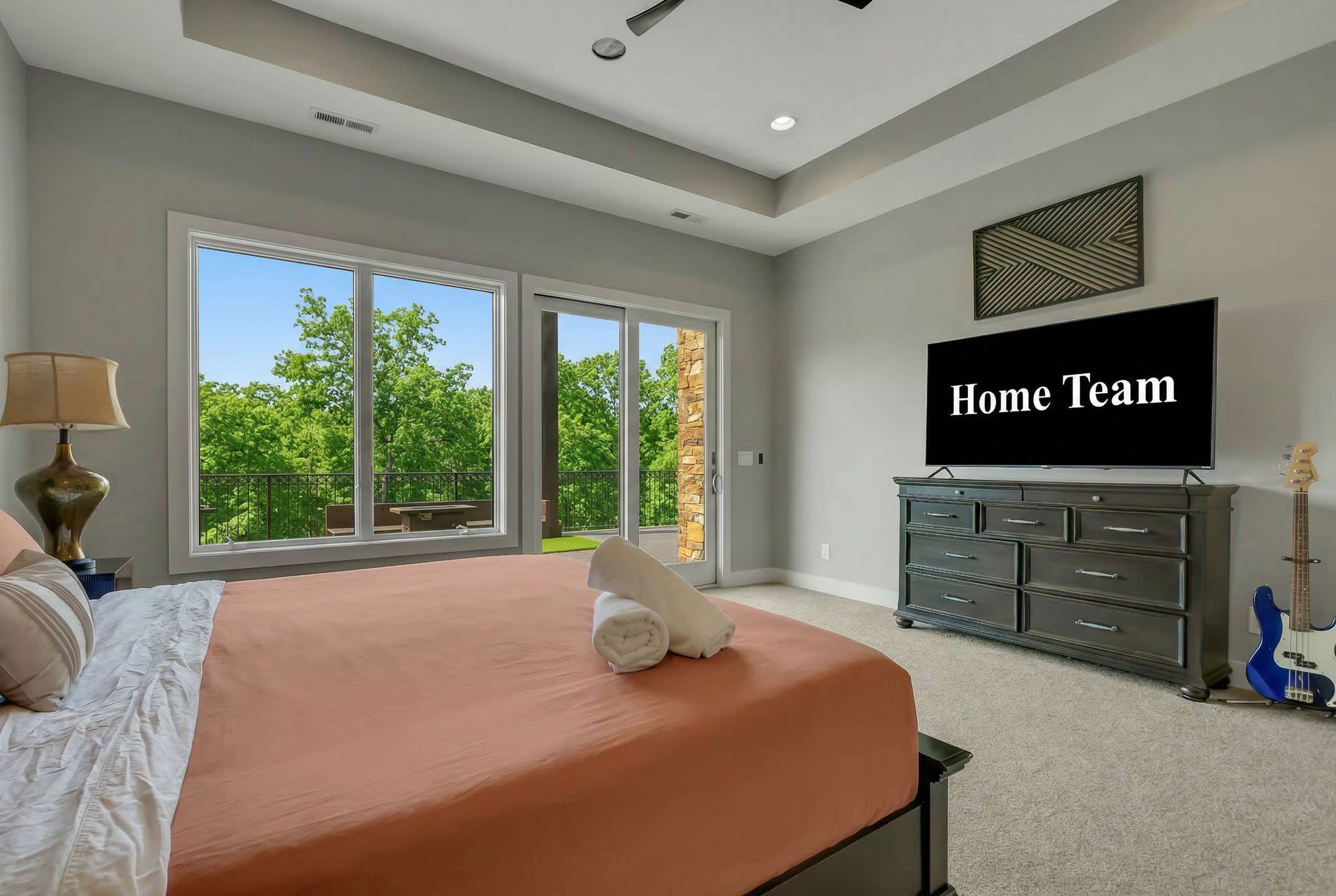 A bedroom with a large bed, a television, and a dresser.