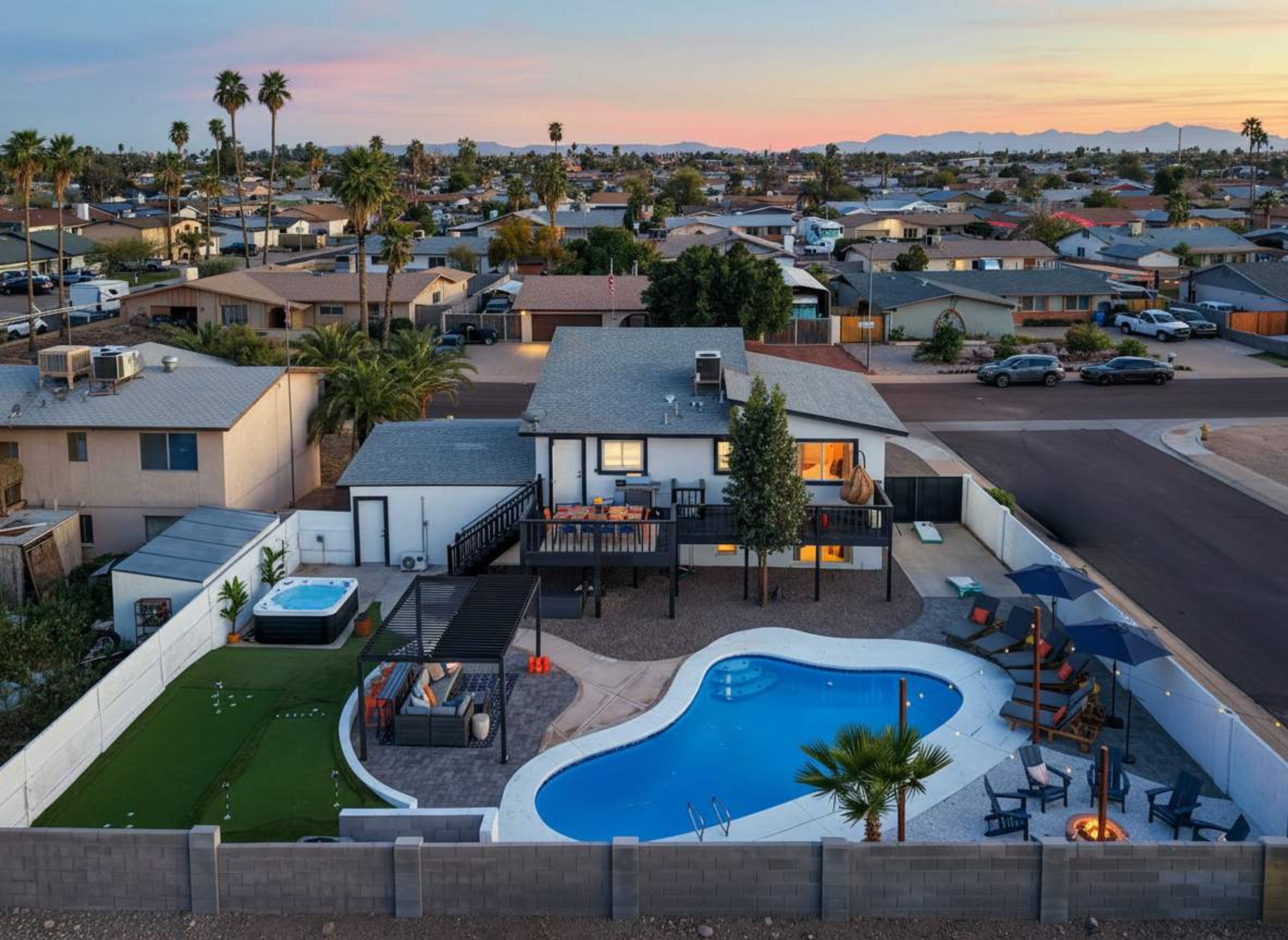 Um bairro residencial com uma casa que tem piscina, área de estar externa e vista para a vizinhança.
