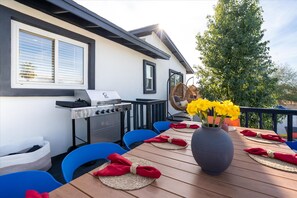 An outdoor dining area with a grill, chairs, and a table set with red napkins. - Piece of Paradise Pool Games Fire Pit Hot tub (Glendale)