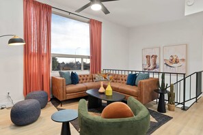 A modern living room with a sectional sofa, a round coffee table, and a green armchair. - Piece of Paradise Pool Games Fire Pit Hot tub (Glendale)