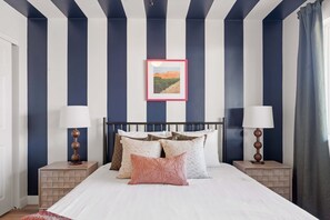 A bedroom with a bed, pillows, a nightstand, a lamp, and a framed picture on the wall. - Piece of Paradise Pool Games Fire Pit Hot tub (Glendale)