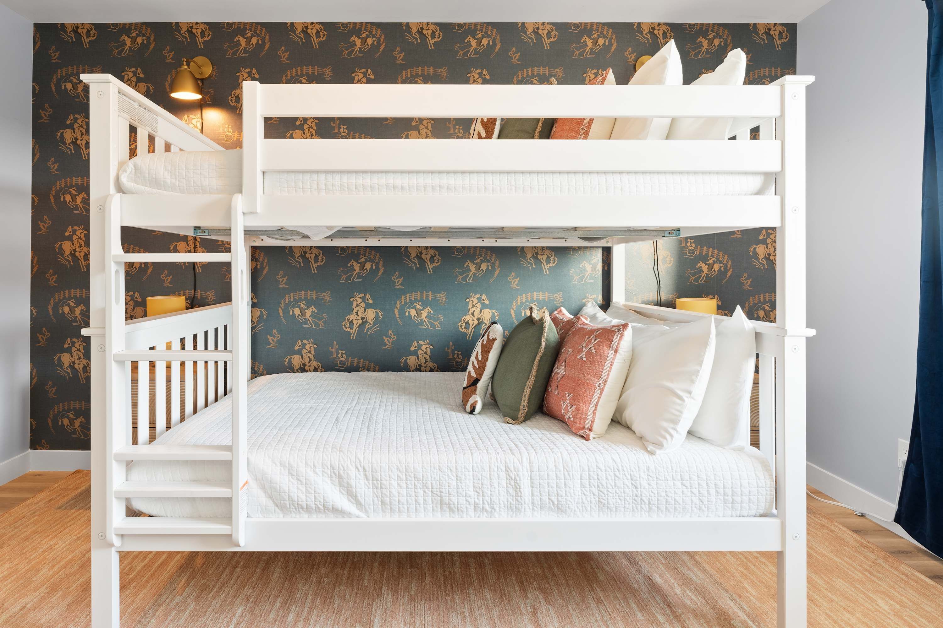 A bunk bed with a white frame, a lower bunk with a quilted mattress, and a top bunk with pillows.