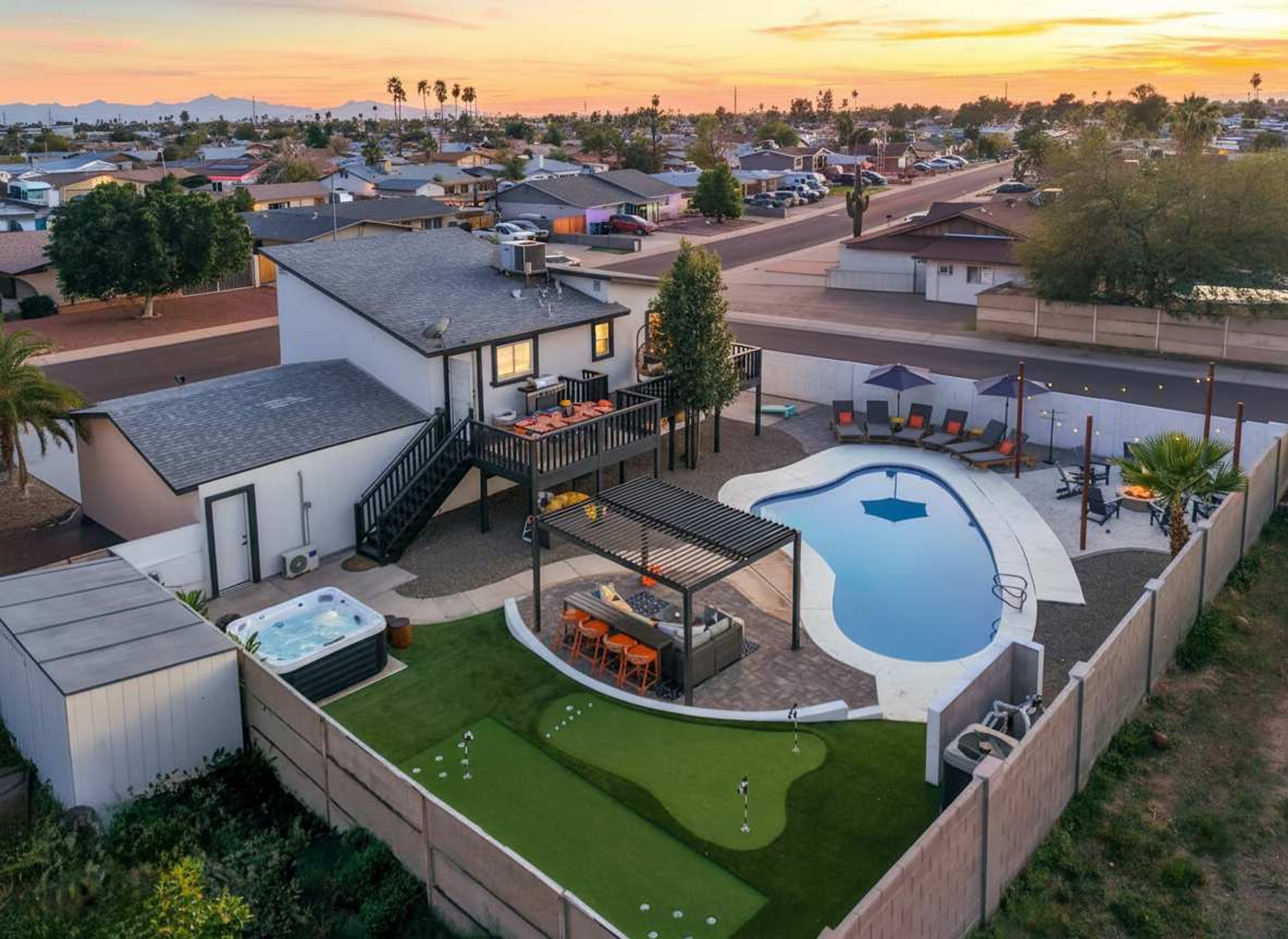 Uma área residencial com piscina, banheira de hidromassagem e um pátio com mobiliário de exterior.