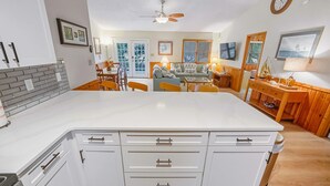 Una cocina moderna con armarios blancos, una isla central y un comedor con sillas de madera.
